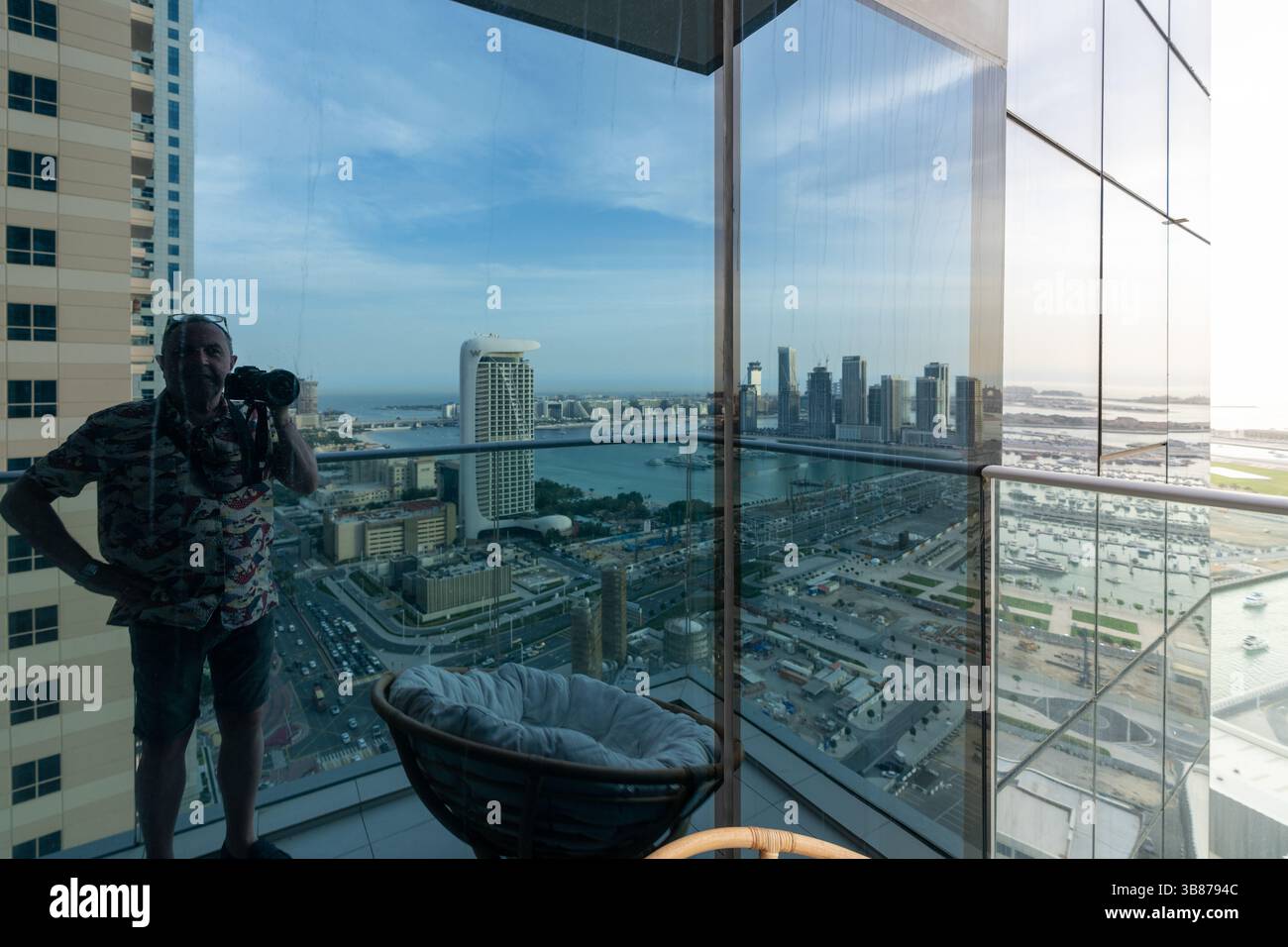 Der Fotograf spiegelt sich in der Wohnung mit Blick auf die Stadt Dubai und den Hafen bei Tageslicht wider Stockfoto