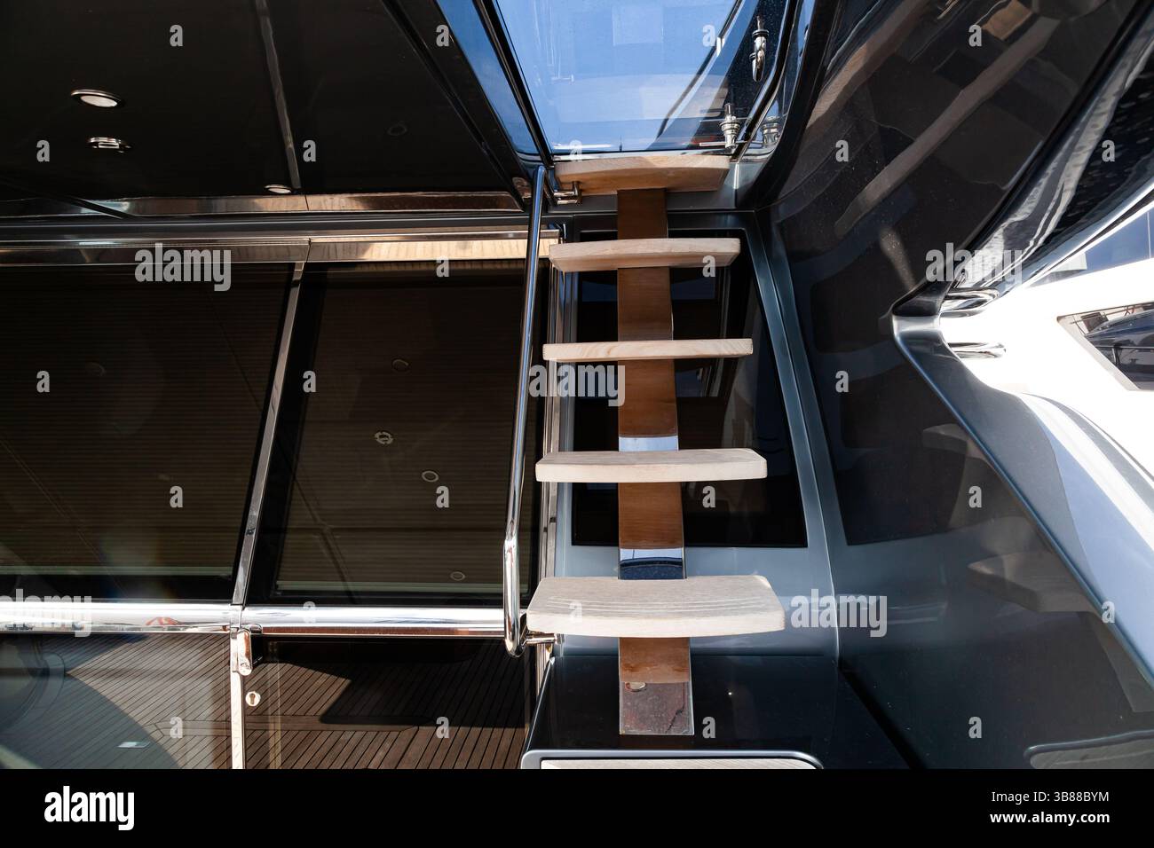 Zugang zum nächsten Stock der Yacht mit einer Holztreppe, Geländern und einer schließenden Luke. Innentreppe auf der Yacht mit Handläufen. Yachteingabe Stockfoto