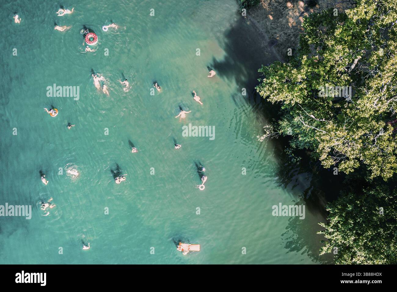 Draufsicht von oben auf die Drohne auf nicht erkennbare Menschen, die im See schwimmen. Wunderschönes blaues Wasser mit vielen Menschen, die am Strand ausruhen, schwimmen und springen Stockfoto