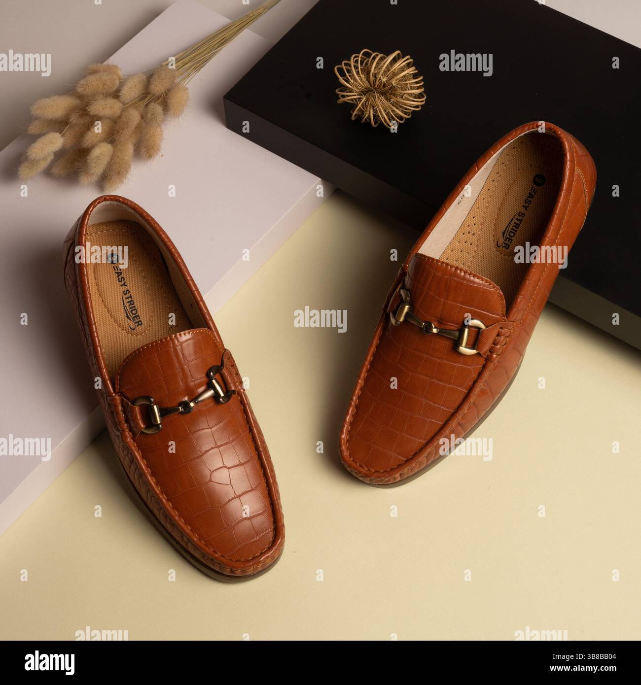 Braune Slipper aus Leder mit Krokodilstruktur und goldener Schnalle für Herren – flach geschnitten Stockfoto