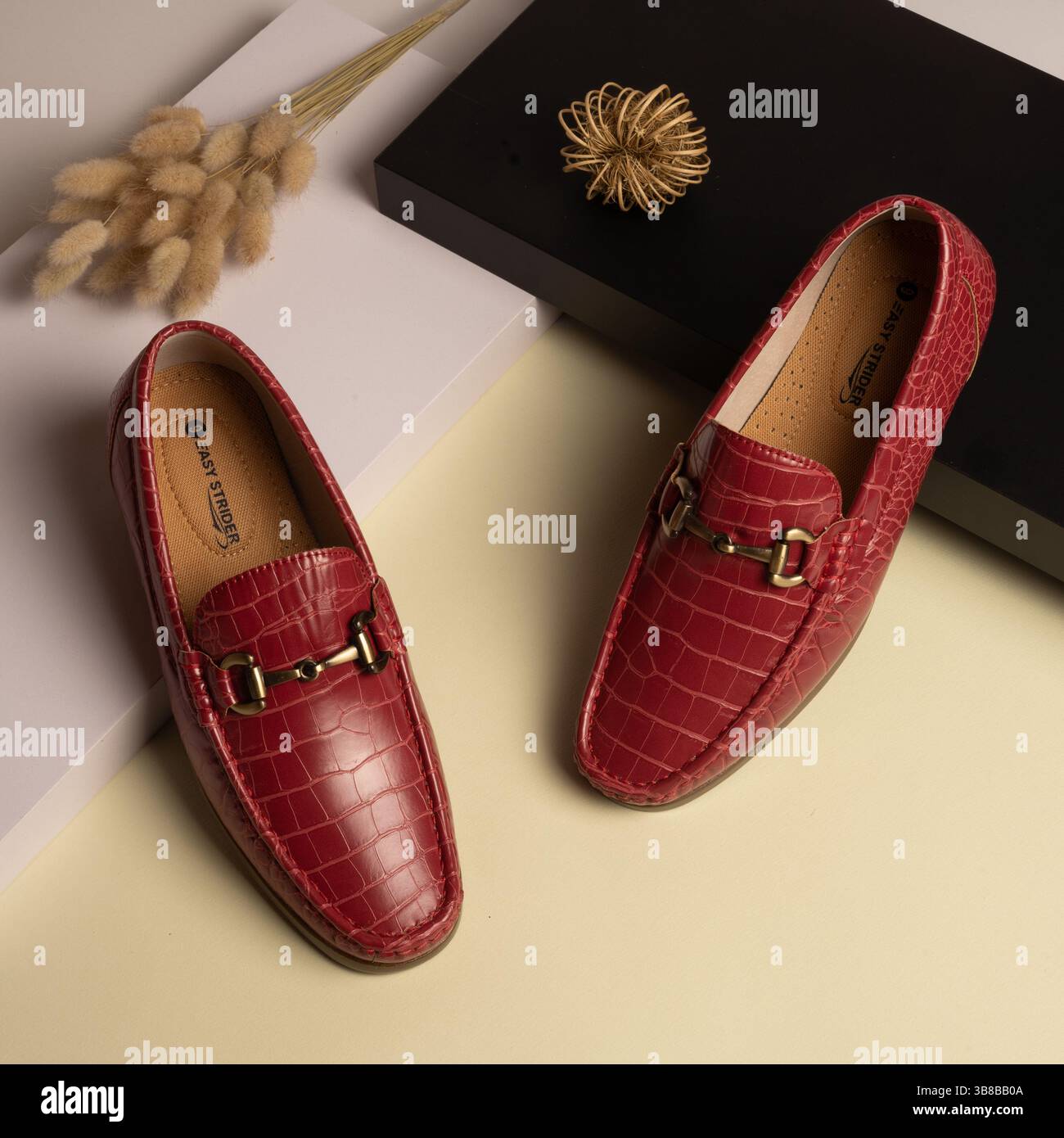 Herren-Slipper aus Leder mit rotem Krokodilmuster und goldfarbener Schnalle Stockfoto