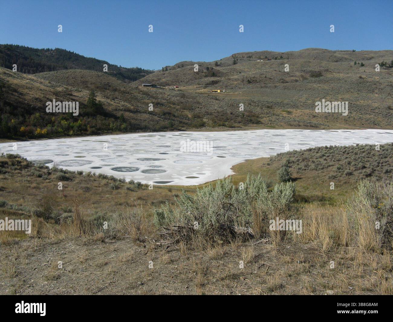 Kreisförmige landwirtschaftliche Flächen bedecken den Boden in einer trockenen, hügeligen Landschaft. Weit entfernte Hügel und karge Vegetation umgeben die einzigartige landwirtschaftliche Praxis SH Stockfoto