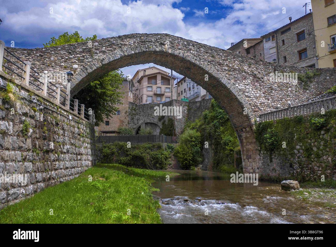 10. Juni 2023, Barcelona, Spanien: Alt und modern: Eine Straßenbrücke überspannt heute den Fluss Llobregat bei La Pobla de Lillet in Katalonien, Spanien, neben der mittelalterlichen Brücke Pont Vell, die in den 1300er Jahren n. Chr. erbaut wurde. Der Pont Vell hat jetzt einen einzigen hohen Esel-Rückenbogen, aber es könnte einmal einen zweiten Bogen gegeben haben und die Quaselsteinfundamente der Säulen deuten auf römische Ursprünge hin (Credit Image: © Sergi Reboredo/ZUMA Press Wire) Stockfoto