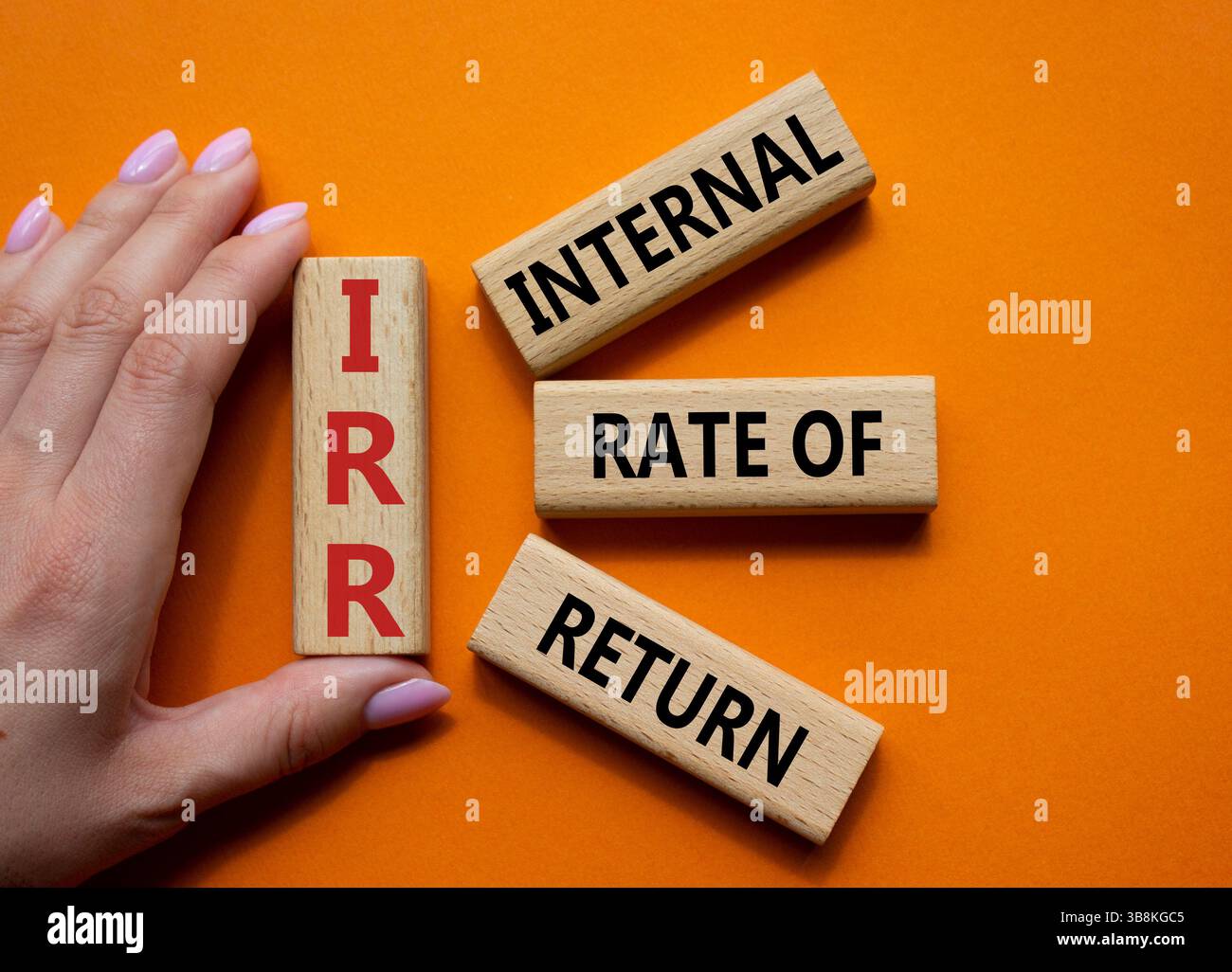 IRR – Symbol für interne Rückkehrrate. Konzeptwort IRR auf Holzwürfeln. Geschäftsmann Hand. Wunderschöner orangefarbener Hintergrund. Business und IRR-Konzept. Kopieren Stockfoto