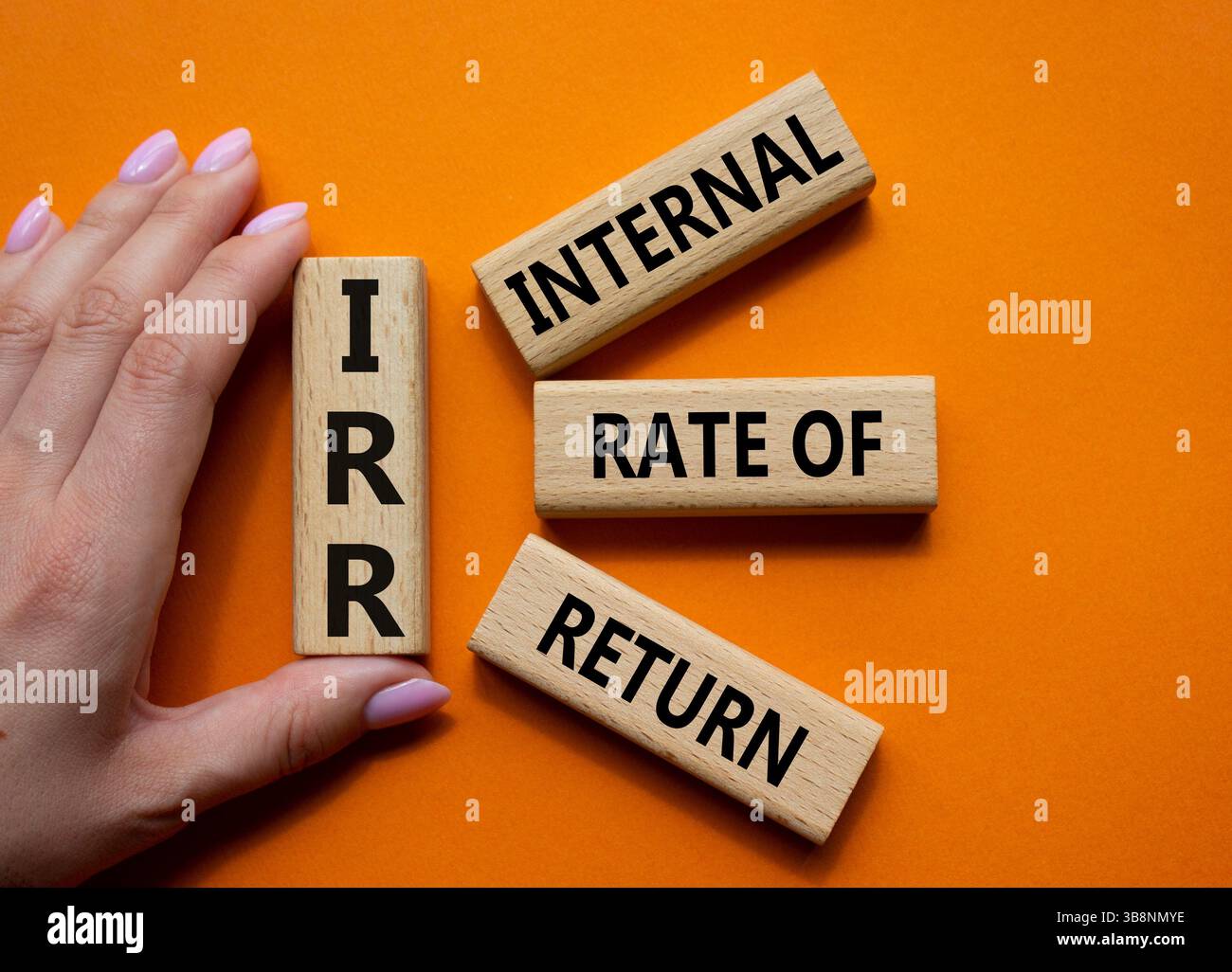 IRR – Symbol für interne Rückkehrrate. Konzeptwort IRR auf Holzwürfeln. Geschäftsmann Hand. Wunderschöner orangefarbener Hintergrund. Business und IRR-Konzept. Kopieren Stockfoto