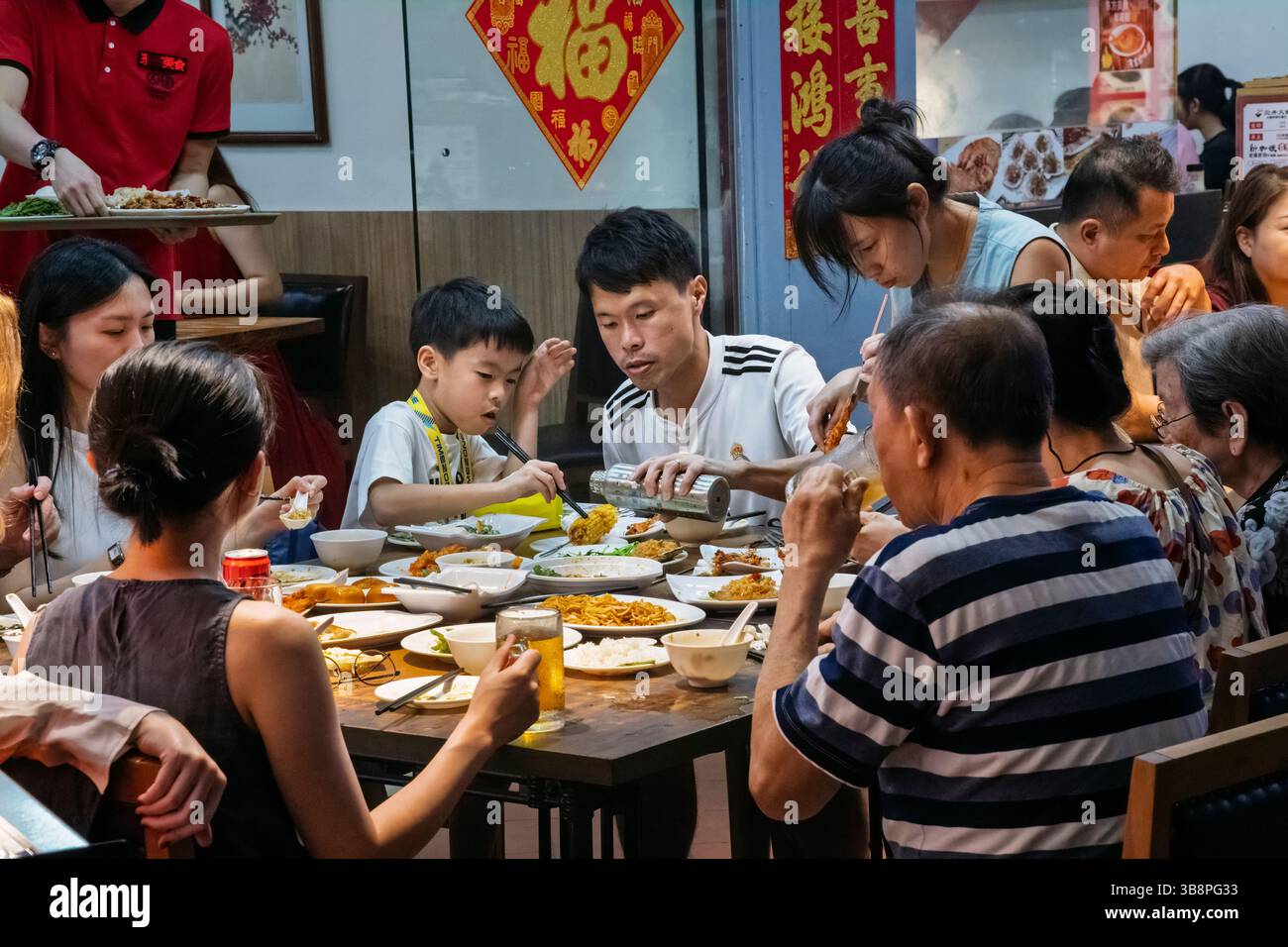 Eine chinesische Familie, die ein Abendessen in einem Restaurant in Chinatown, Singapur genießt Stockfoto