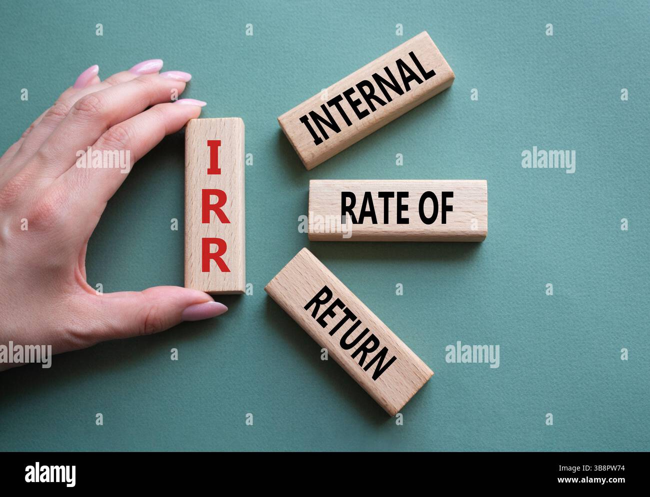 IRR – Symbol für interne Rückkehrrate. Konzeptwort IRR auf Holzwürfeln. Geschäftsmann Hand. Wunderschöner graugrüner Hintergrund. Business und IRR-Konzept. C Stockfoto