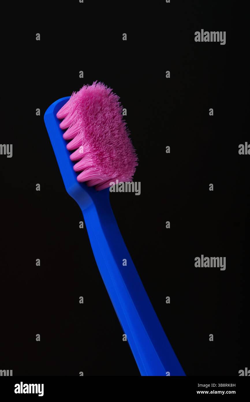 Benutzte Plastikzahnbürste mit rosa Borsten auf schwarzem Hintergrund. Keime. Es ist Zeit, es wegzuwerfen und durch ein neues zu ersetzen. Stockfoto