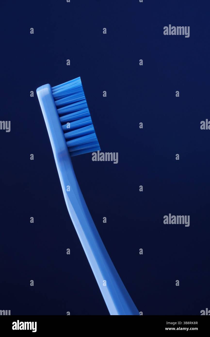 Blaue Plastikzahnbürste auf dunkelblauem Hintergrund. Mundhygiene. Zahnheilkunde. Stockfoto