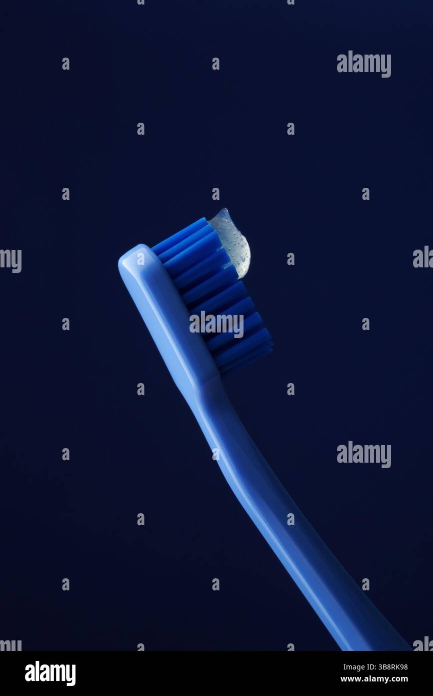 Blaue Plastikzahnbürste auf dunkelblauem Hintergrund mit transparenter Zahnpasta. Mundhygiene. Zahnheilkunde. Stockfoto