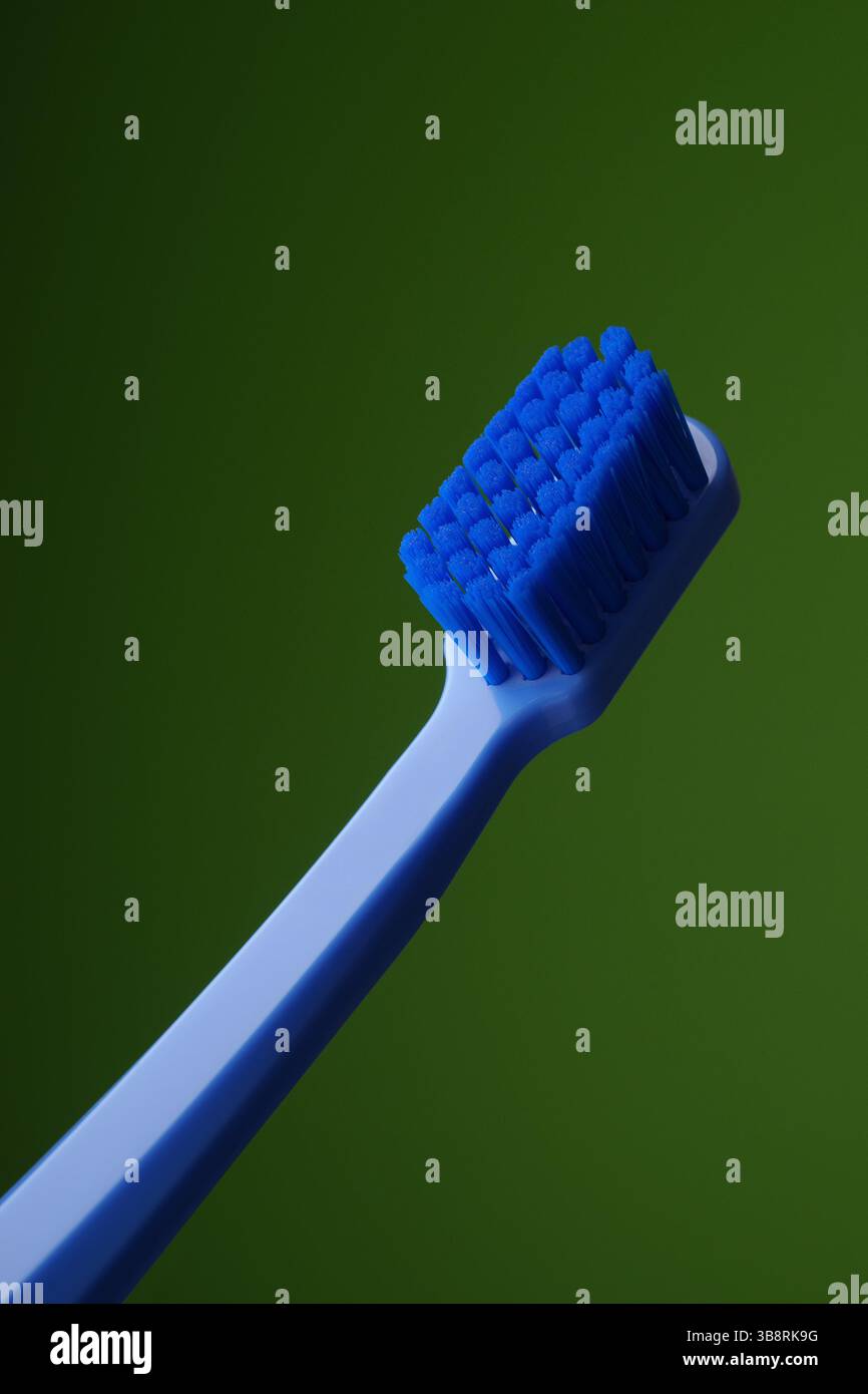 Blaue Plastikzahnbürste auf grünem Hintergrund. Mundhygiene. Empfehlungen des Zahnarztes. Morgenroutine. Stockfoto