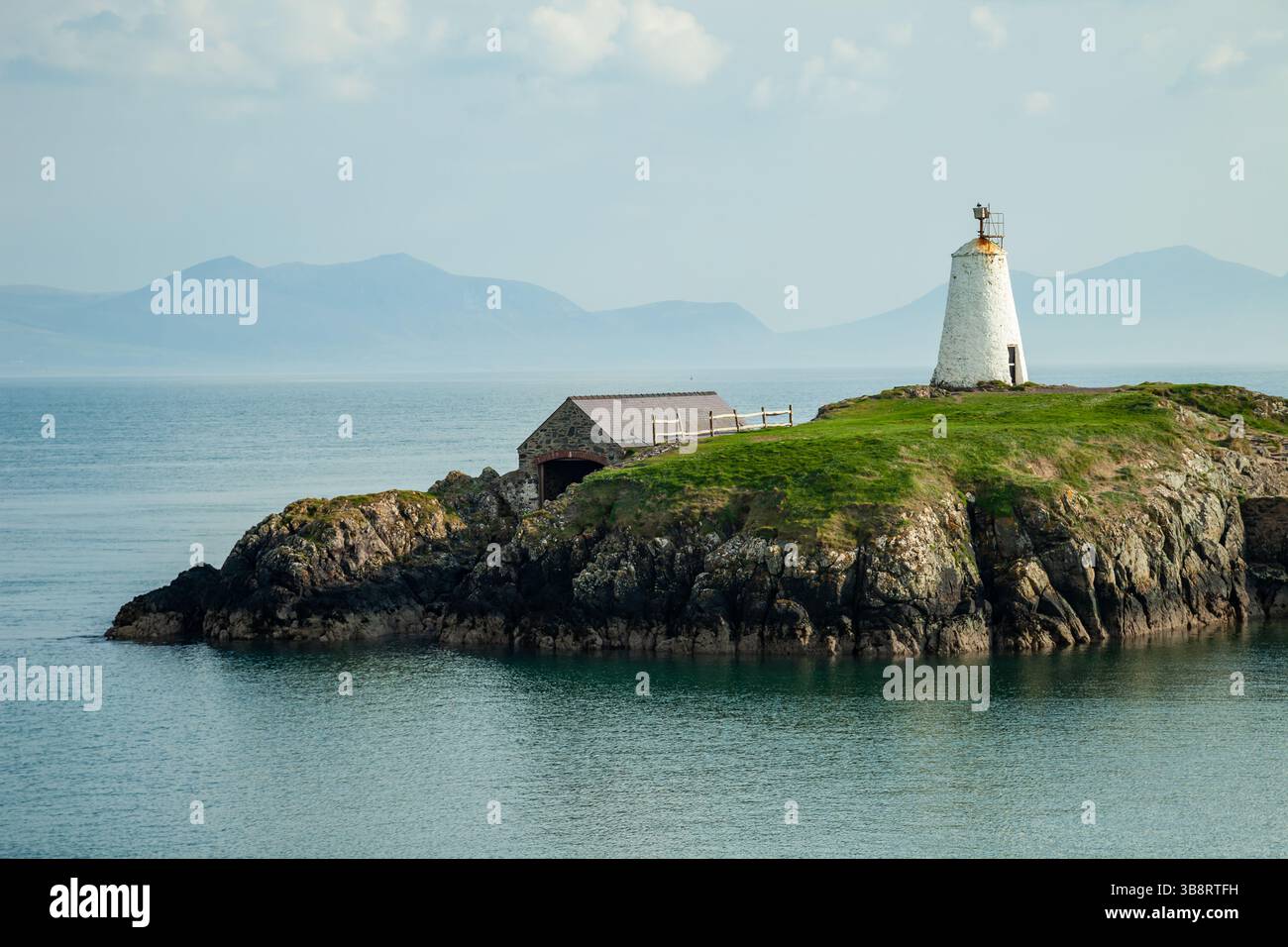 Frühlingsnachmittag am TWR Bach Leuchtturm auf Llanddwyn Island, Anglesey, Wales. Die Gipfel von Snowdonia erheben sich in der Ferne. Stockfoto