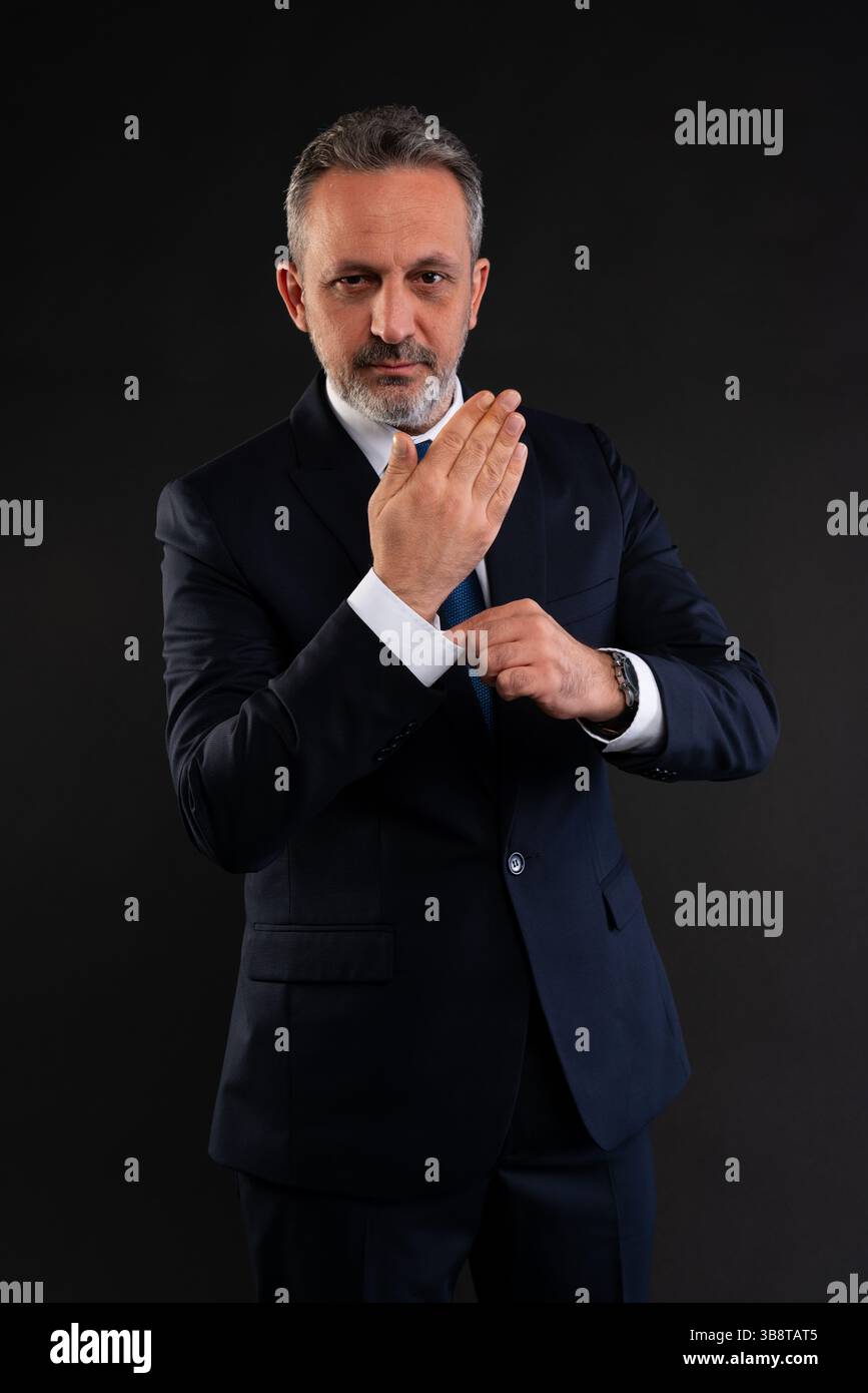 Porträt eines selbstbewussten, Reifen Geschäftsmannes, der seine Hemdmanschette anpasst, während er in die Kamera blickt. Stilvoll und professionell. Stockfoto