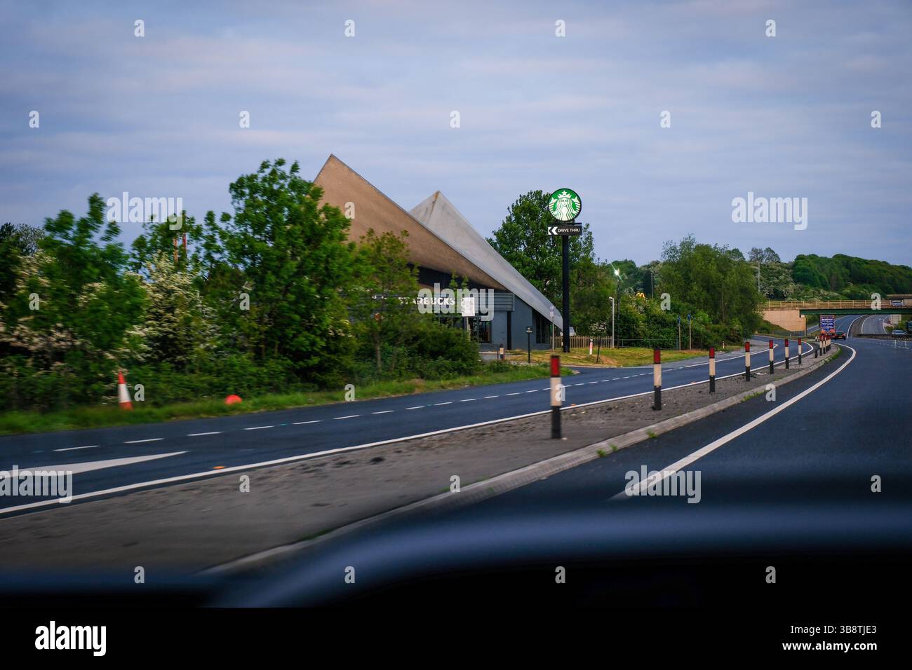 07. Mai 2025 - Peterborough, Großbritannien - Blick auf die Starbucks Drive Thru-Schilder vom Fahrersitz eines Autos auf der Autobahn Stockfoto