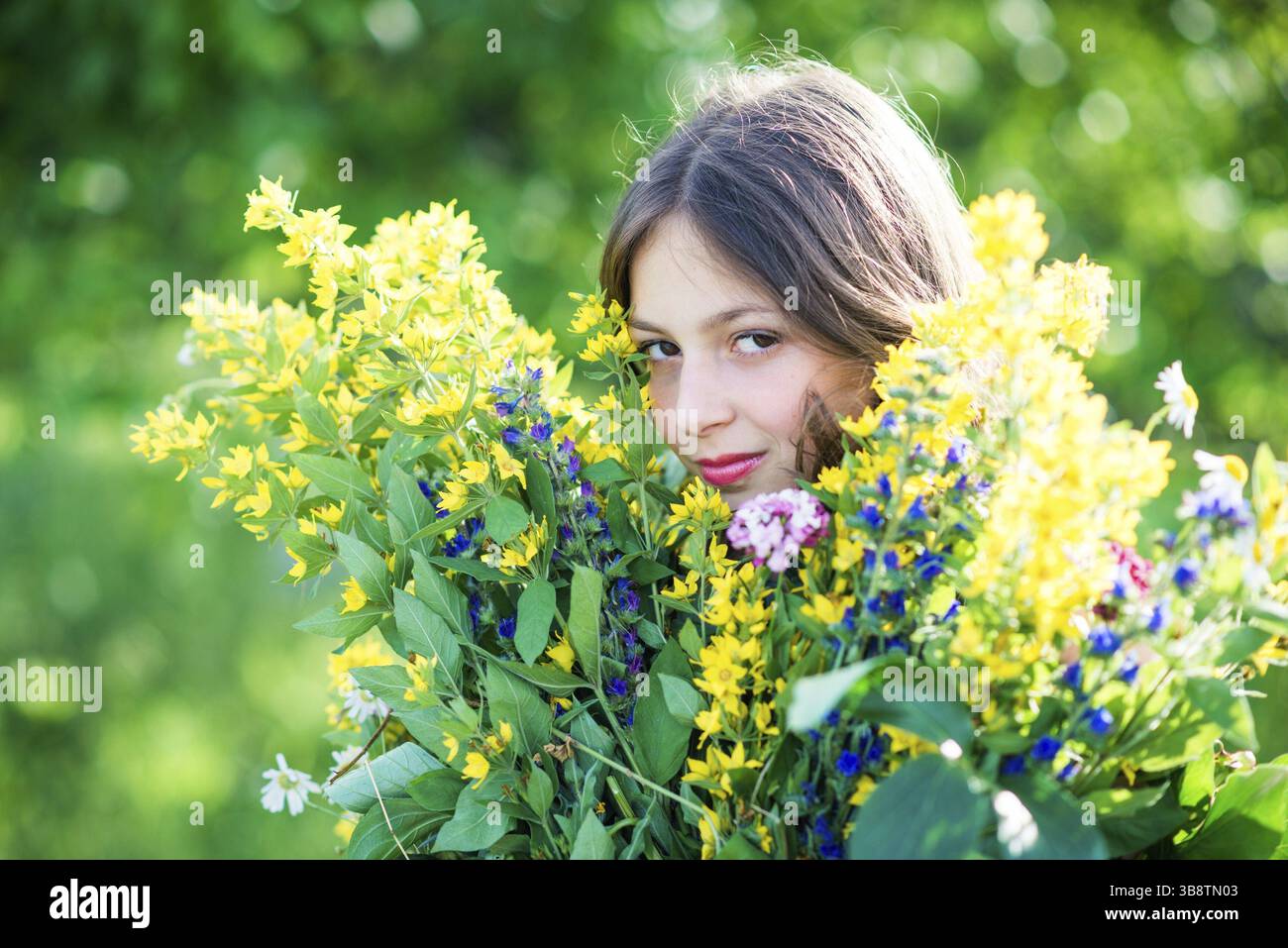 Porträt eines Mädchens mit Blumen am sonnigen Sommertag Stockfoto