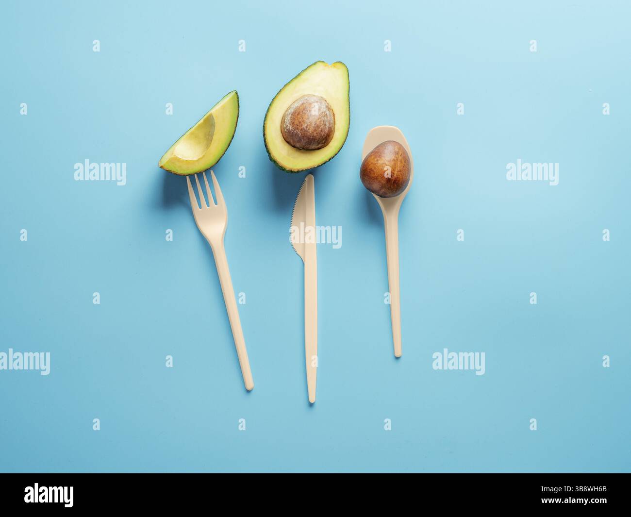 Avocado Seeds Biologisch Abbaubares Einmalbesteck. Biokunststoff – eine großartige Alternative zu Einwegbesteck aus Kunststoff. Minimales Konzept auf blauem Hintergrund Stockfoto