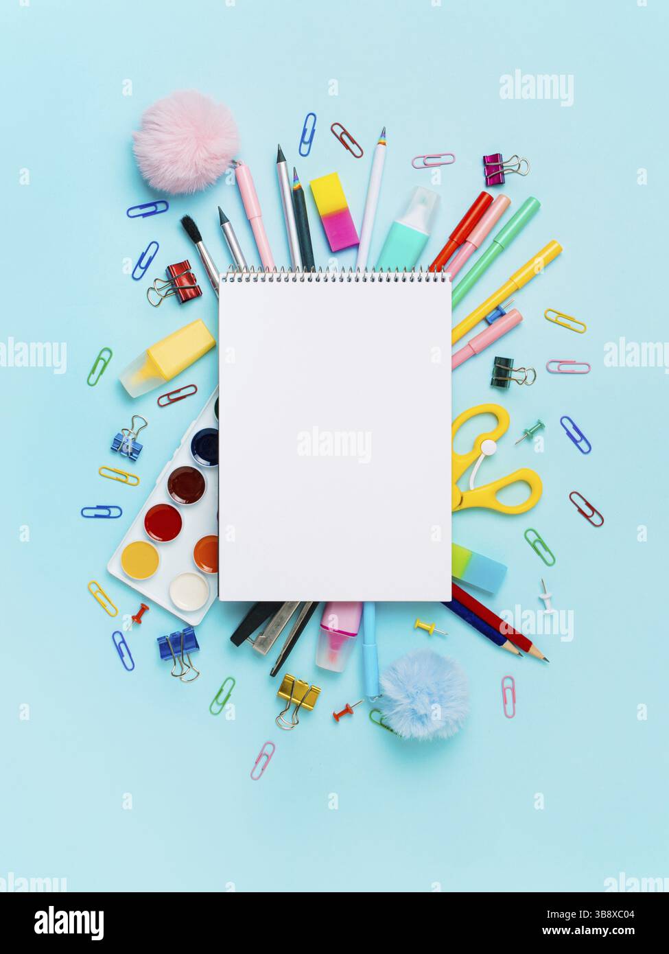 Notizbuch mit stationären Objekten auf blauem Hintergrund. Leeres weißes Papierblatt mit Notizblock oder Skizzenbuch über Schulbedarf, isoliert auf blau. Vertikal. Stockfoto