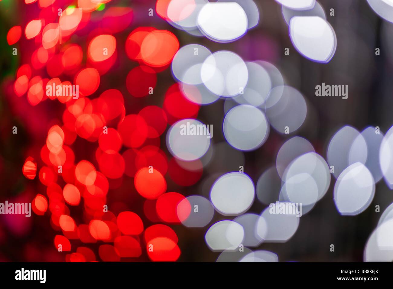 Abstrakte bunte Bokeh-Kugeln auf dunklem Hintergrund, lebendiges, defokussiertes Lichtpunktmuster, festliche Overlay-Textur für Fotobearbeitung, unscharfer, heller Zirkus Stockfoto