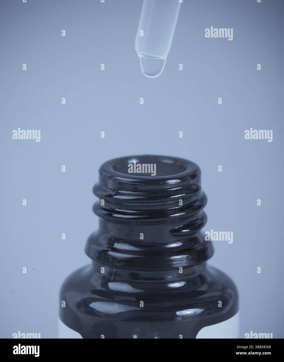 Glasflasche mit Pipette auf blauem Hintergrund Stockfoto