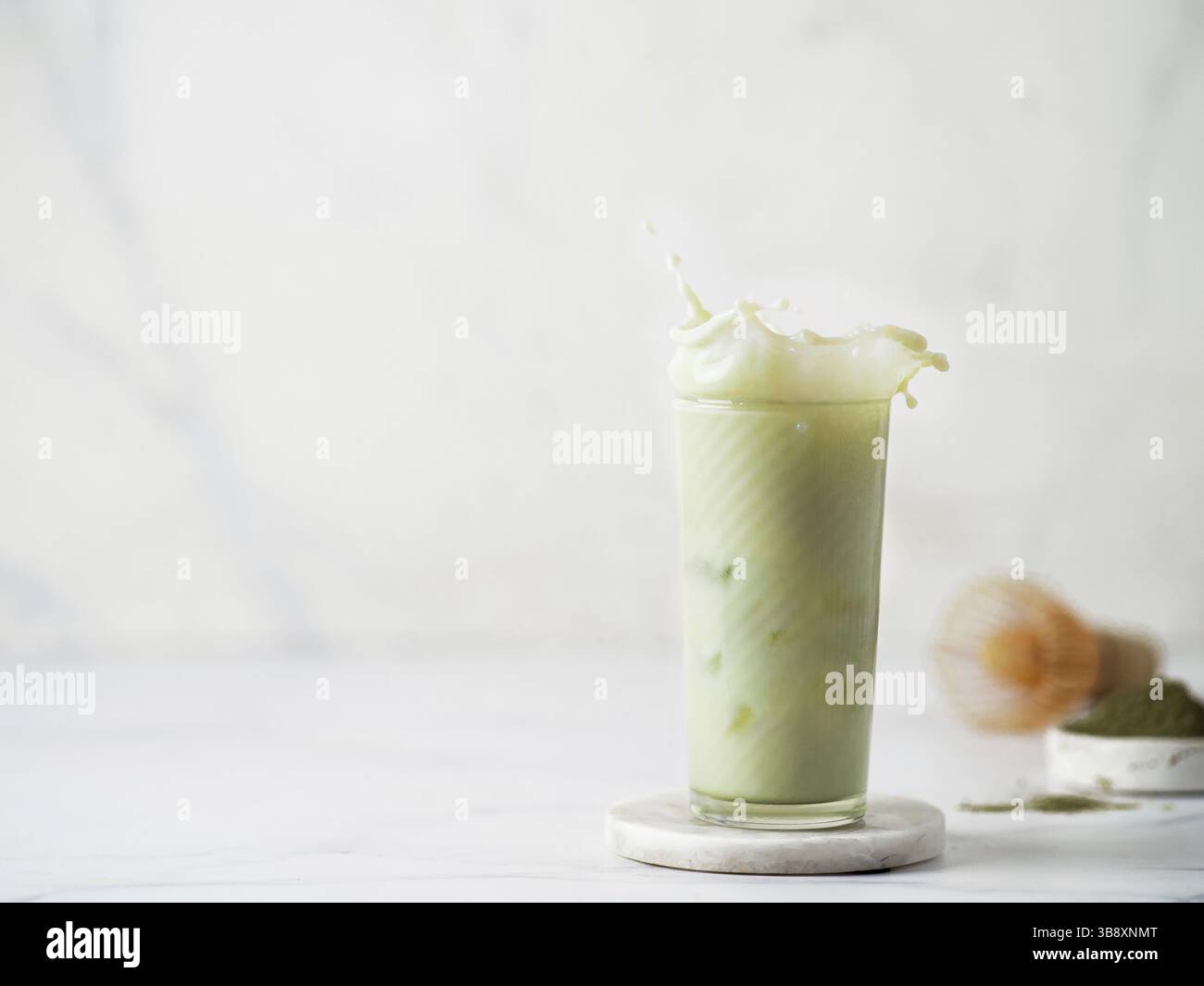 Hausgemachte Eistee Matcha Latte mit Spritzer auf weißem Hintergrund. Kopieren Sie Platz für Text oder Design Stockfoto