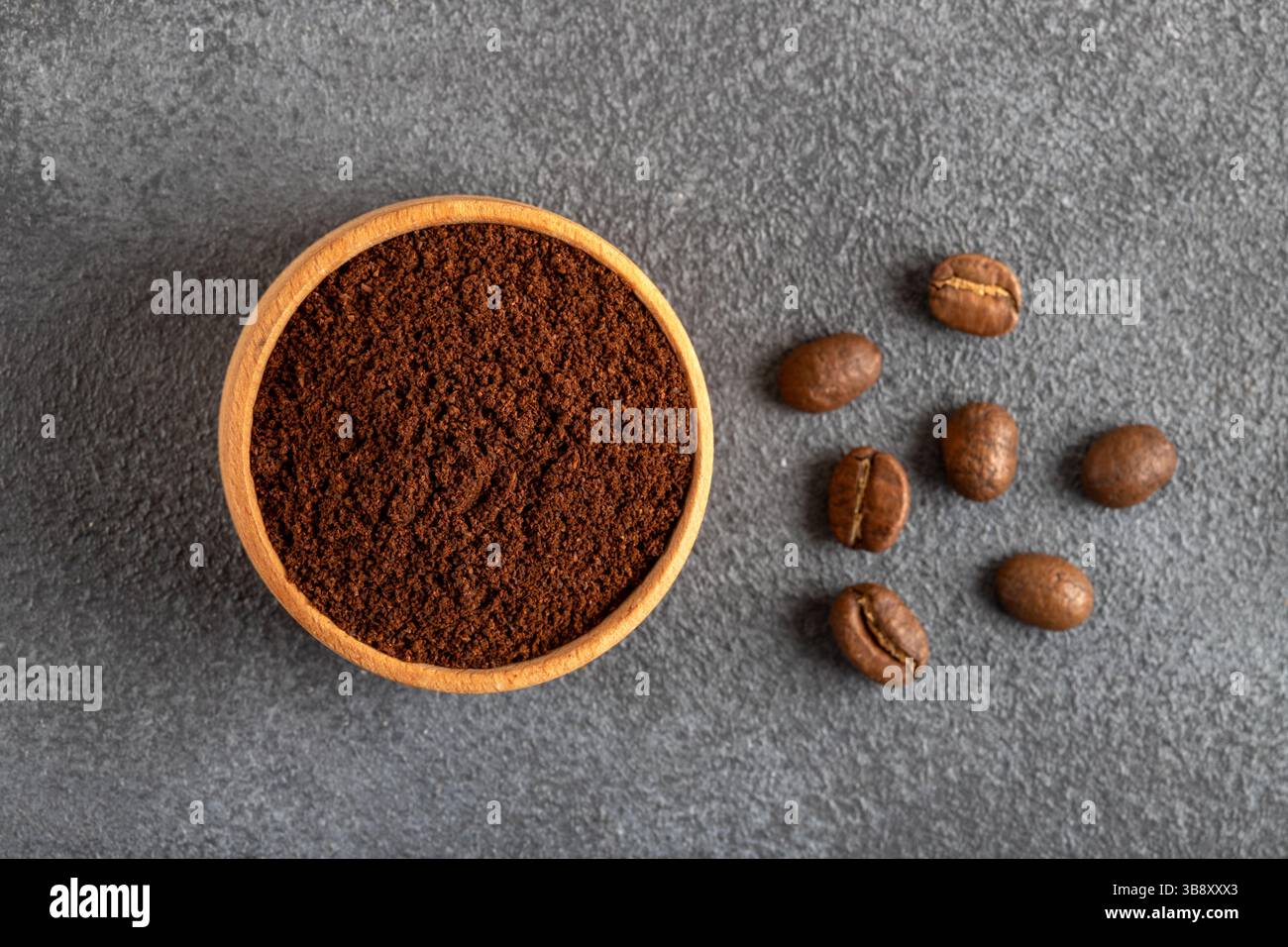 Kaffeebohnen mit einer Schüssel gemahlenen Kaffees auf schwarzem Hintergrund Stockfoto