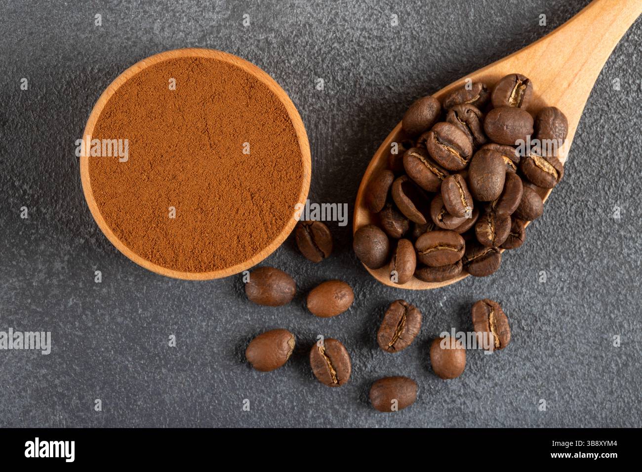 Kaffeebohnen mit einer Schüssel gemahlenen Kaffees auf schwarzem Hintergrund Stockfoto