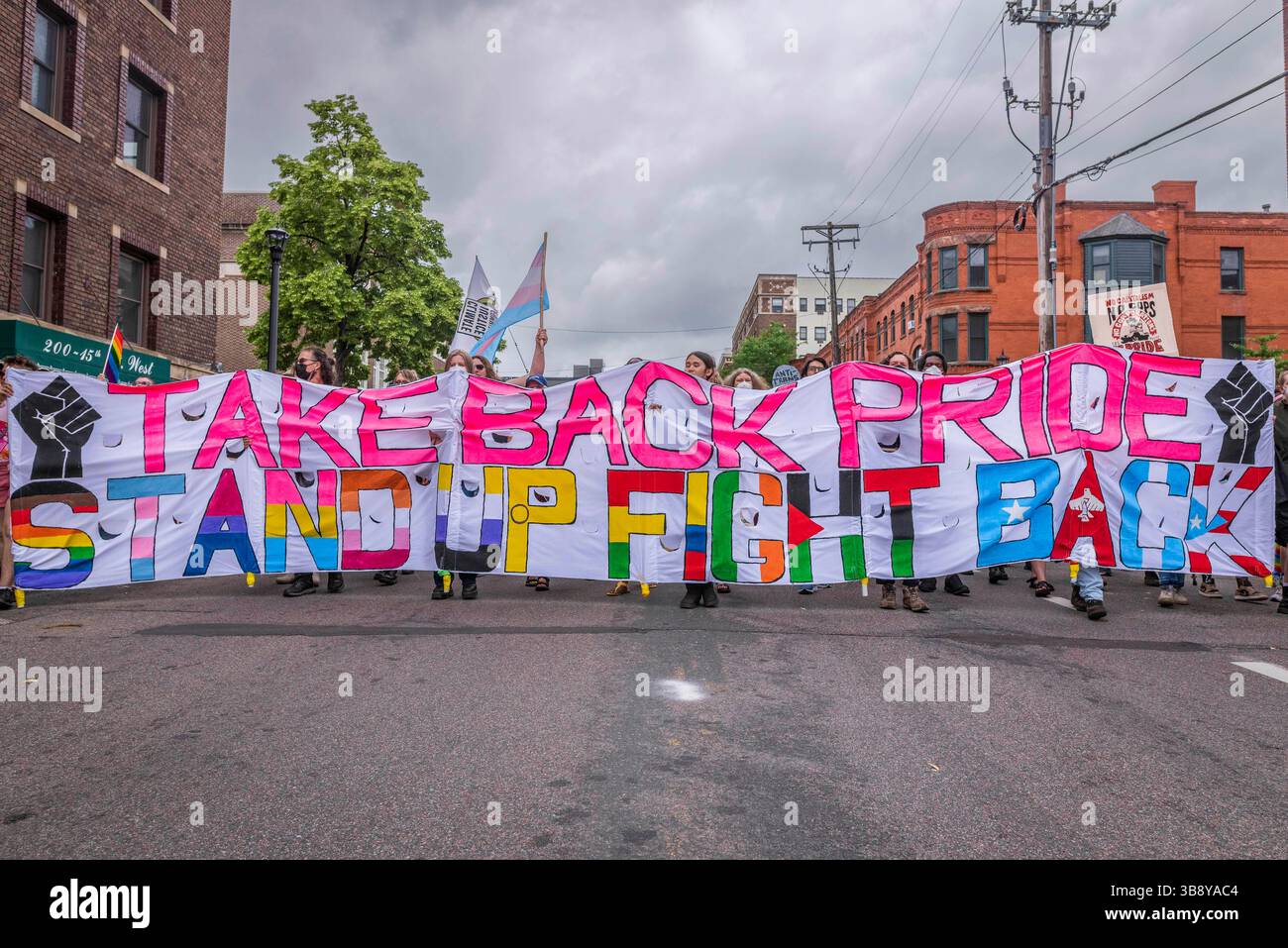 25. Juni 2023, Minneapolis, Minnesota, USA: Demonstranten tragen ein großes Banner mit der Aufschrift „Take Back Pride – Stand Up Fight Back“. Als Reaktion auf den Einfluss der Unternehmen und der Polizei auf die Twin Cities Pride-Feier führte die Take Back Pride Coalition ihren jährlichen Protest aus. Die Gruppe marschierte entlang der Hennepin Avenue und endete im Loring Park. Stockfoto