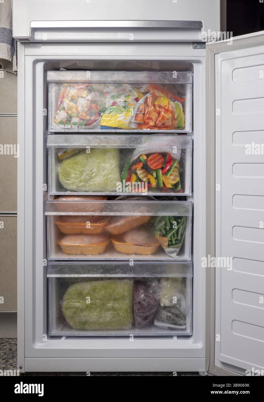 Geöffneter Gefrierkühlschrank mit gefrorenem Gemüse und Fleisch. Krise der gefrorenen Lebensmittelversorgung, Lebensmittelvorräte für Quarantäneabsperrung Stockfoto