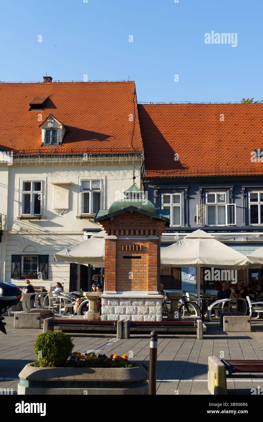 Ein gemütliches Café im Freien mit Sonnenschirmen, umgeben von bezaubernden Gebäuden im europäischen Stil mit roten Ziegeldächern Stockfoto