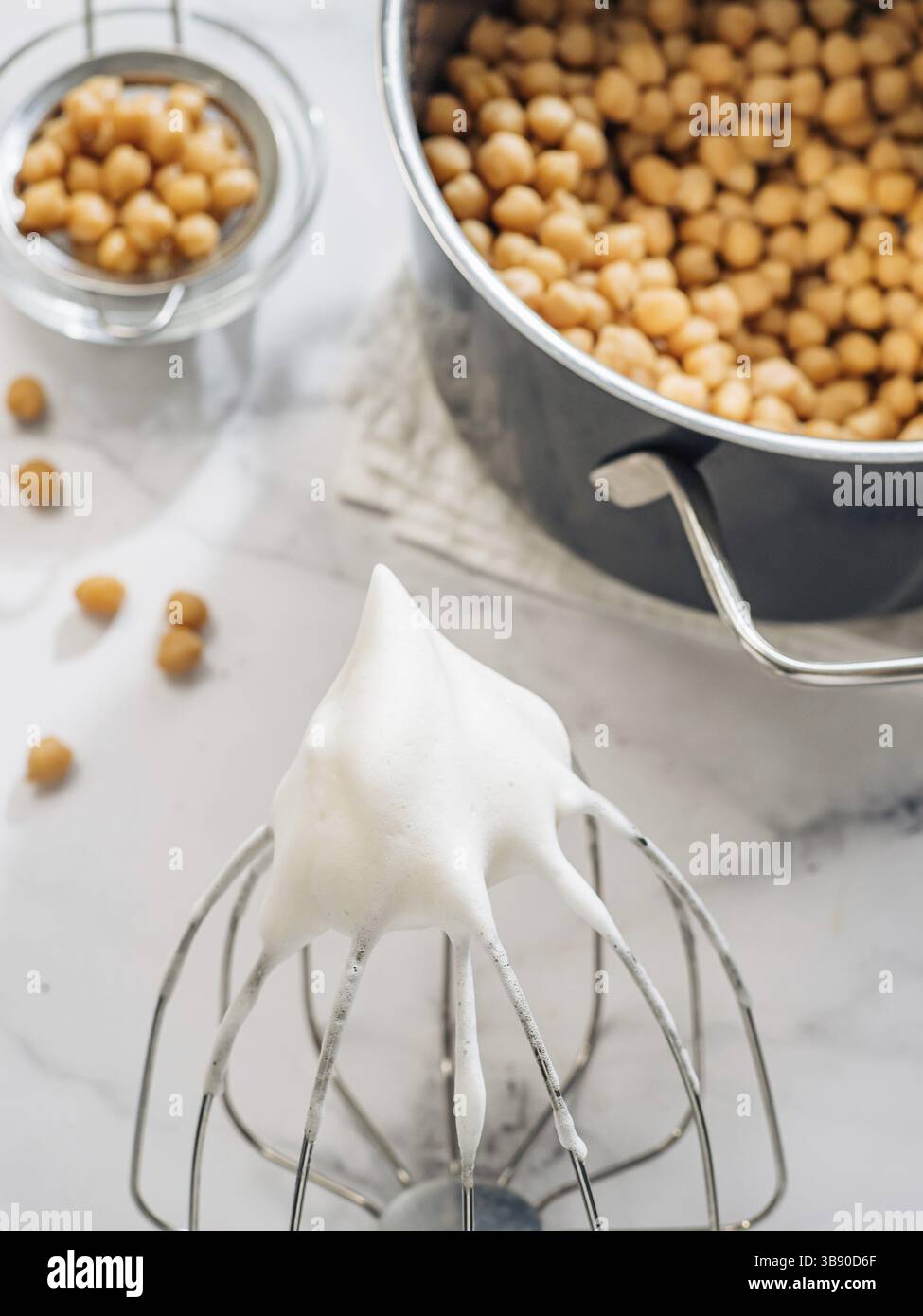Gepeitschter aquafaba auf Planetenmischer Schneebesen, vertikal. Kichererbsen Wasser Sole aquafaba peitscht. Eierersatz beim Gurren. Veganes Konzept. Draufsicht oder fl Stockfoto