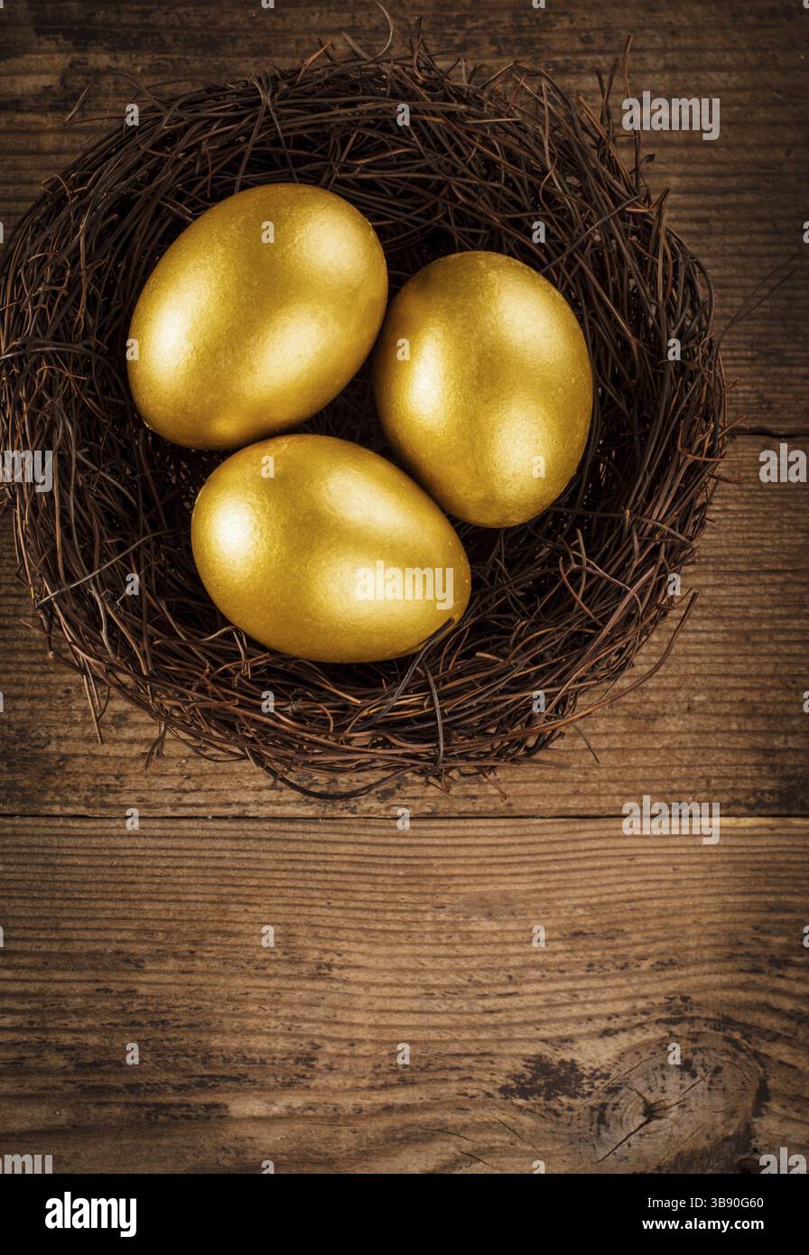 Goldene Eier im Nest auf hölzernem Hintergrund mit Text Stockfoto