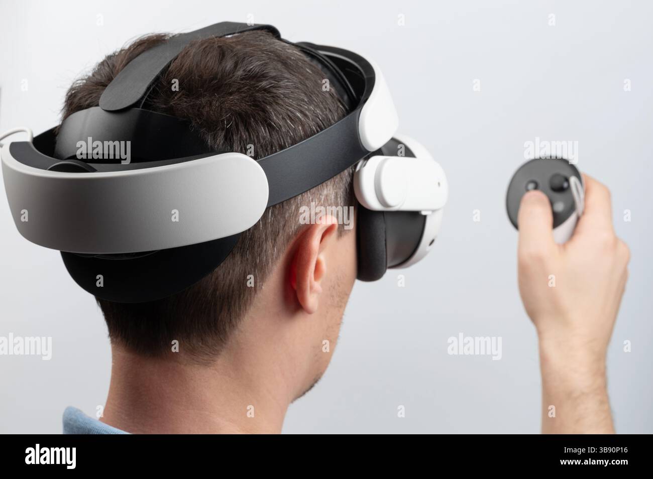 Der Benutzer nutzt die Virtual-Reality-Technologie, trägt ein Headset und hält den Controller in einem gut beleuchteten Raum. Stockfoto