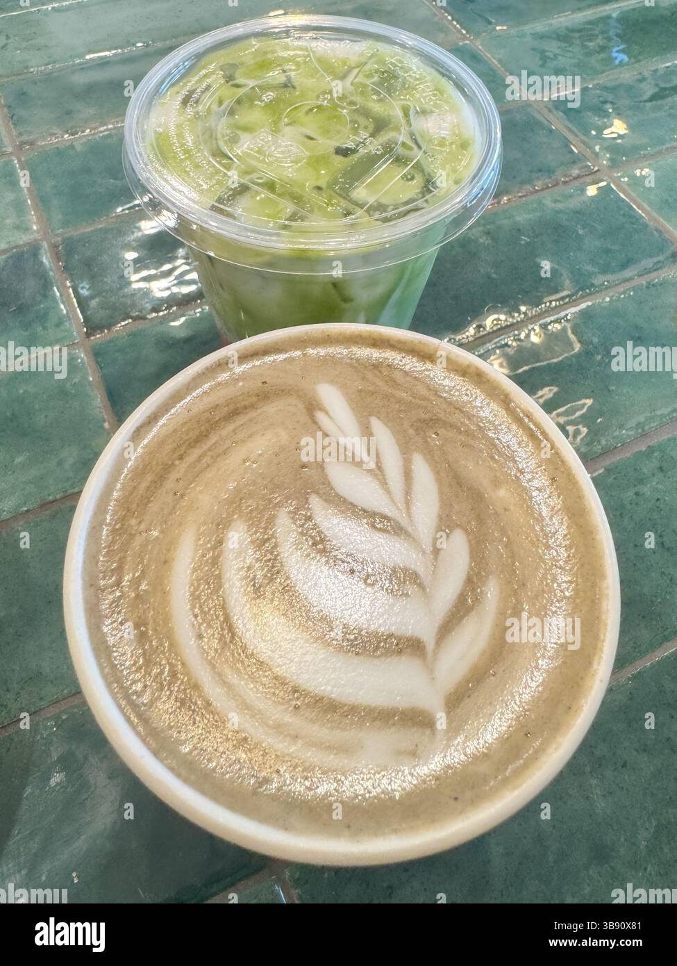 Kaffee-Latte und Matcha-Latte werden nebeneinander auf einer lebendigen grünen Fliesentheke in einem stilvollen Café serviert und bieten perfekte moderne Getränke Stockfoto