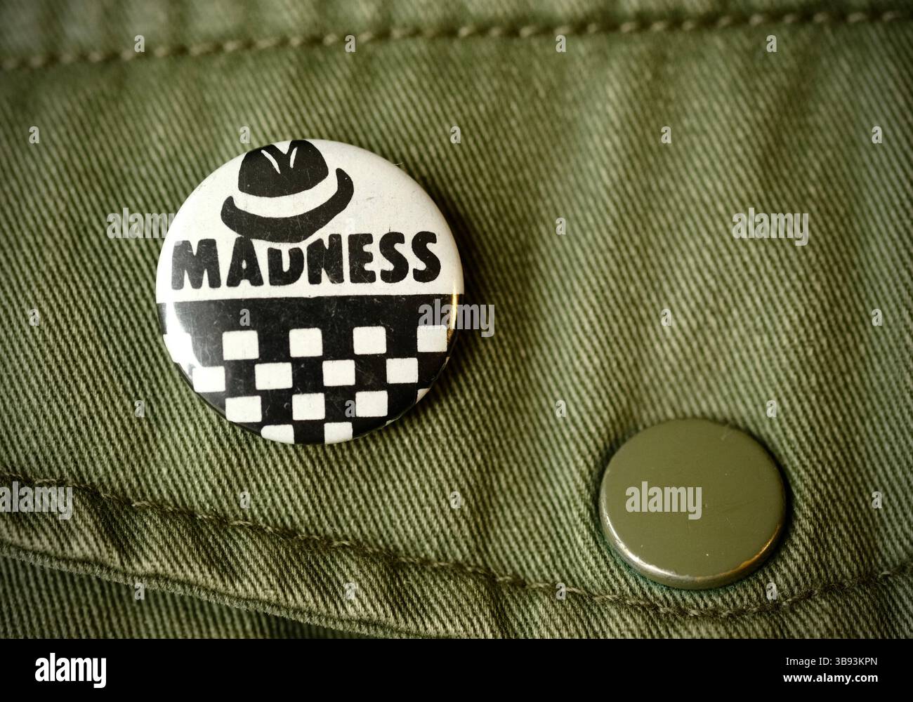 Vintage Wahnsinn Ska Musikband Emaille Pin Badge auf grünem Hintergrund aufgenommen im Mai 20205, Herefordshire Stockfoto