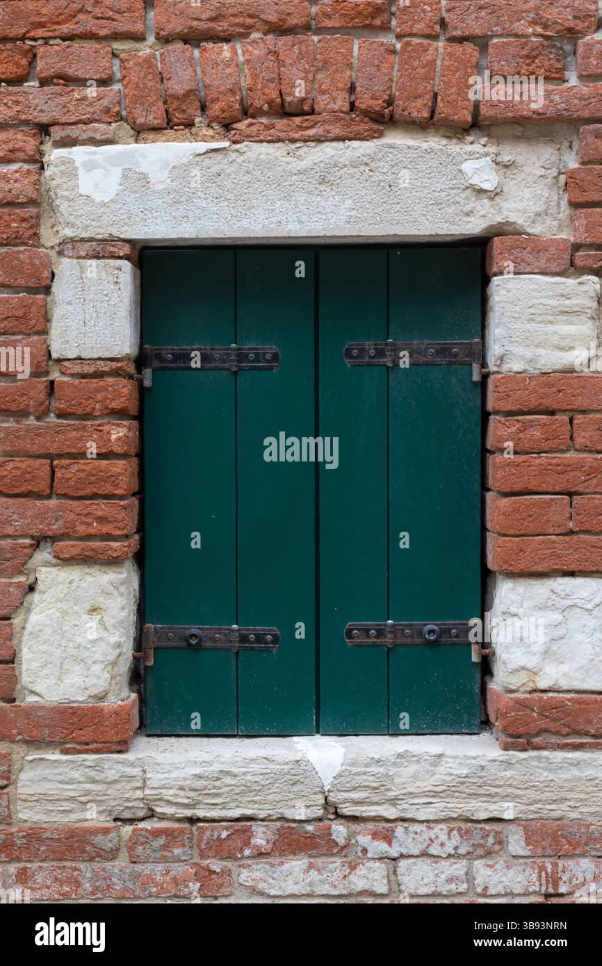 Grüne Fensterläden an Ziegelstein und Steinmauer Stockfoto