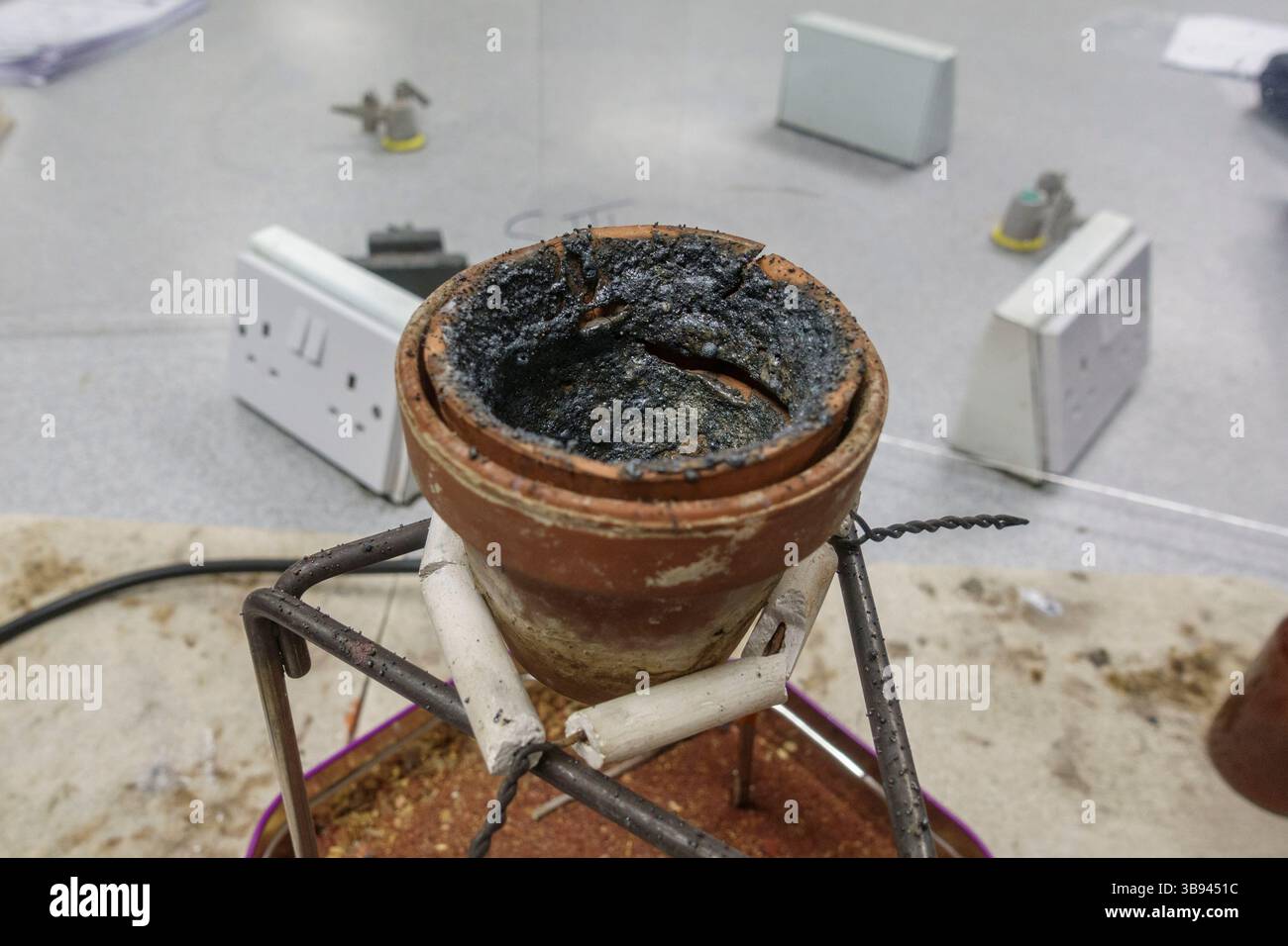 Der Terrakotta-Topf bleibt nach einer Thermitreaktion (Eisen(III)-oxid und Aluminiumpulver) in einer britischen Sekundarschule erhalten. Stockfoto
