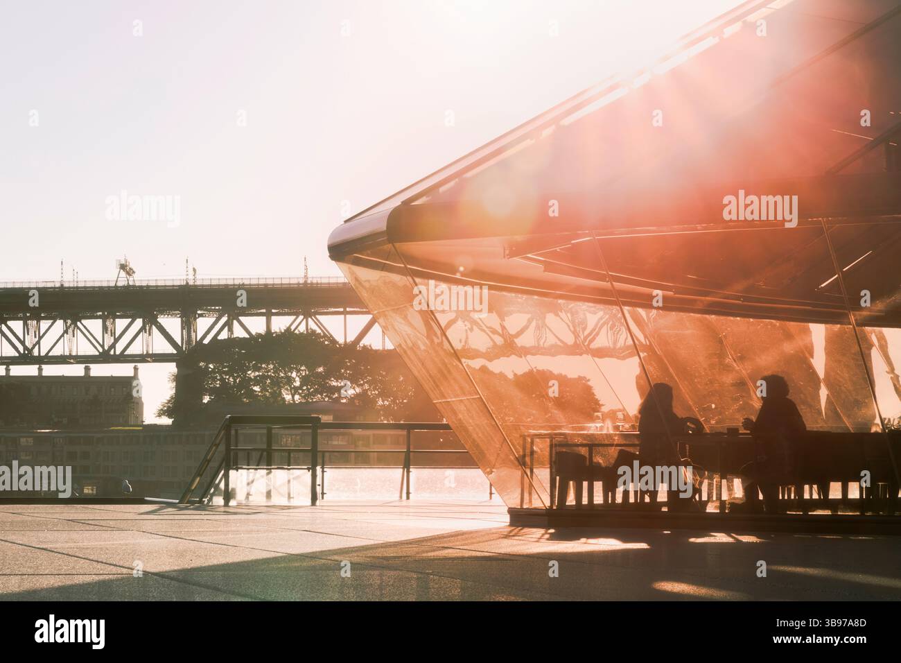 Romantischer Abend in einem Hafencafé im Sydney Opera House mit Sonnenfackeln und der berühmten Sydney Harbour Bridge im Hintergrund Stockfoto