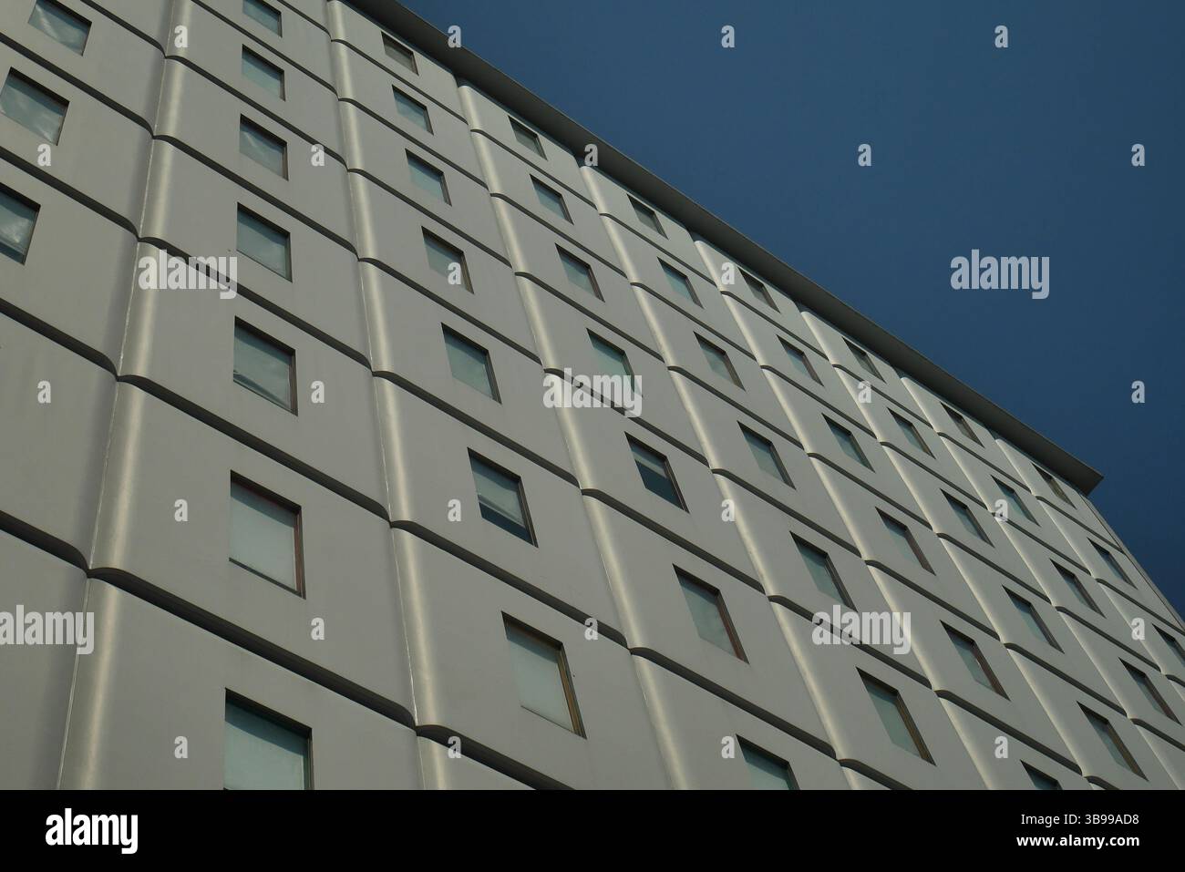 Flacher Blick, das Fenstermuster in einem mehrstöckigen Gebäude ohne Balkon. Stockfoto