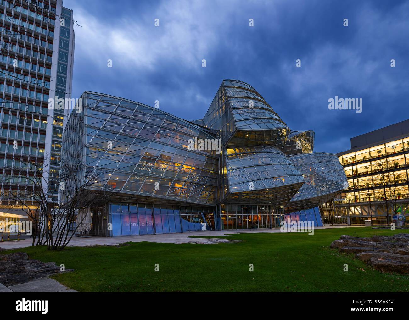 Basel, Schweiz - 09. Dezember 2024: Das Gehry-Gebäude der Firma Novartis zur blauen Stunde. Es wurde von Frank O. Gehry entworfen – ein futuristisches Glas an Stockfoto