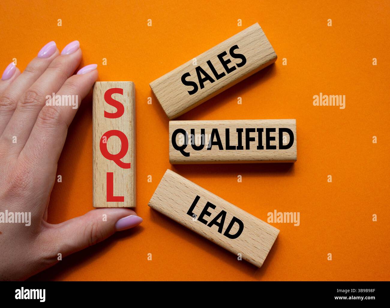 SQL - qualifizierter Lead für Vertrieb. Holzwürfel mit SQL-Wörtern. Geschäftsmann Hand. Wunderschöner orangefarbener Hintergrund. Business- und SQL-Konzept. Kopierbereich. Stockfoto