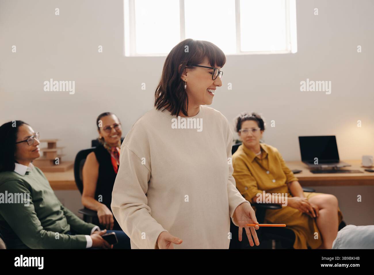 Eine erfolgreiche Geschäftsinhaberin, die ein Team-Meeting in einem modernen Büroumfeld einlädt. Hervorheben von Zusammenarbeit, Führungsqualitäten und Professionalität Stockfoto