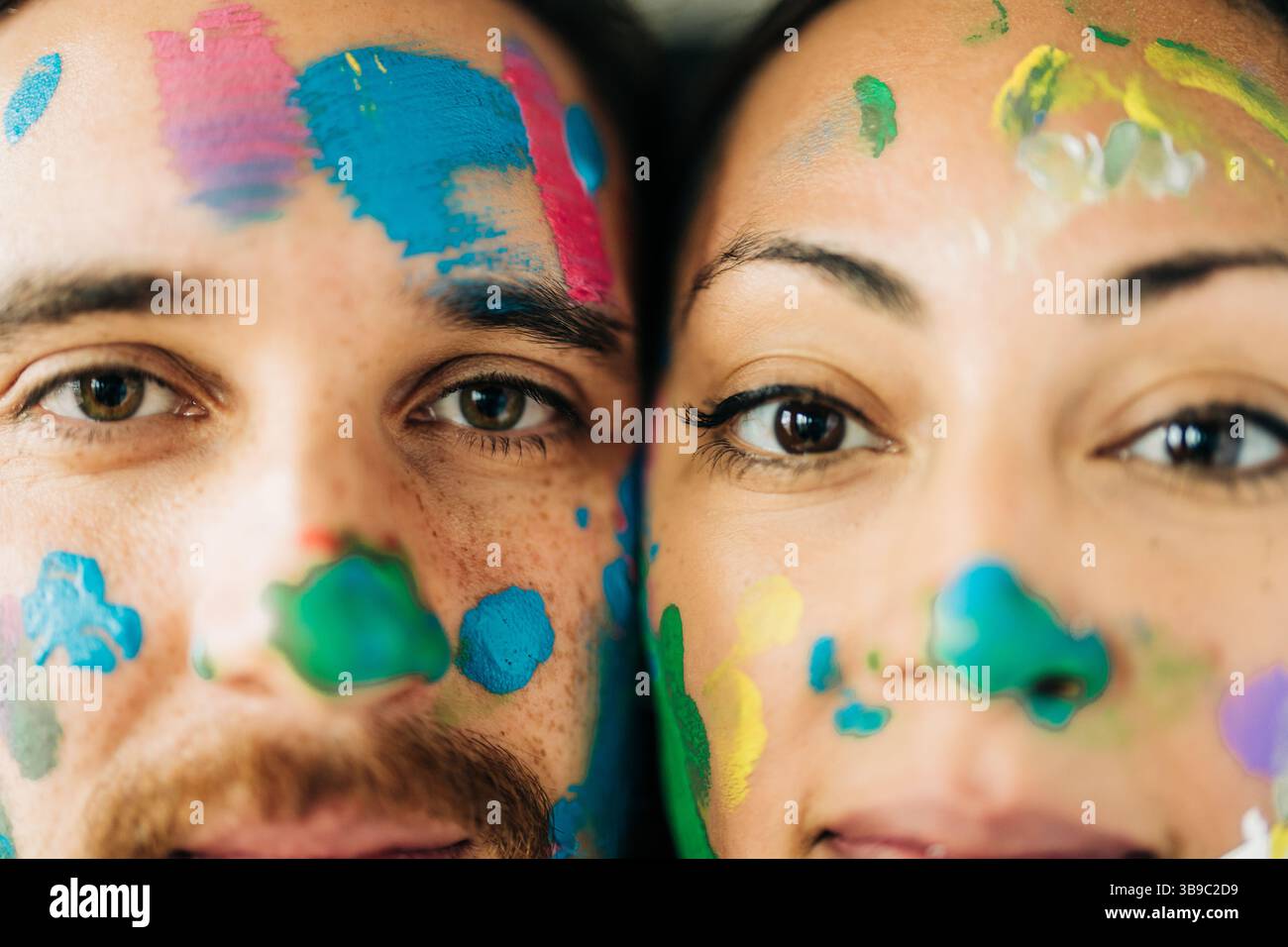 Extreme Nahaufnahme der Gesichter von Paaren, die mit hellen Farbspritzern bedeckt sind Stockfoto