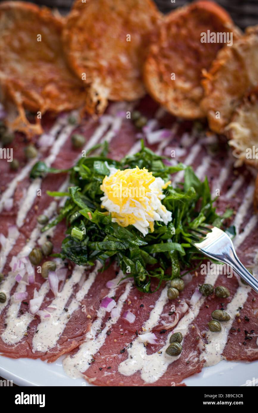 Carpaccio-Schale mit Garnitur und Kapern vertikal Stockfoto