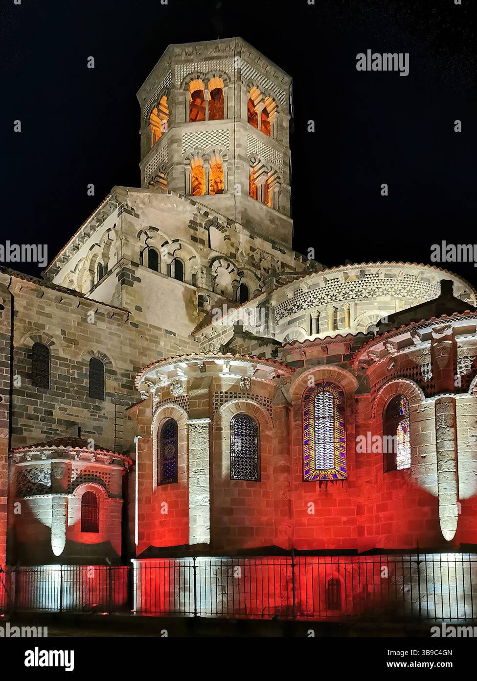 Beleuchtete Abbatiale Saint Austremoine in Issoire bei Nacht mit Puy de Dome in der französischen Region Auvergne Rhone Alpes - Smartphone-aufgenommenes Stockfoto