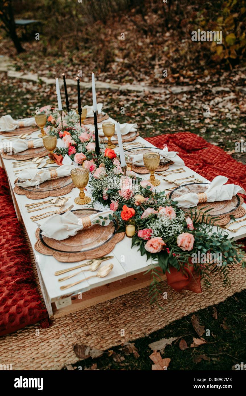 Boho Herbst Hochzeit Picknick auf Teppich mit frischen Blumen Stockfoto