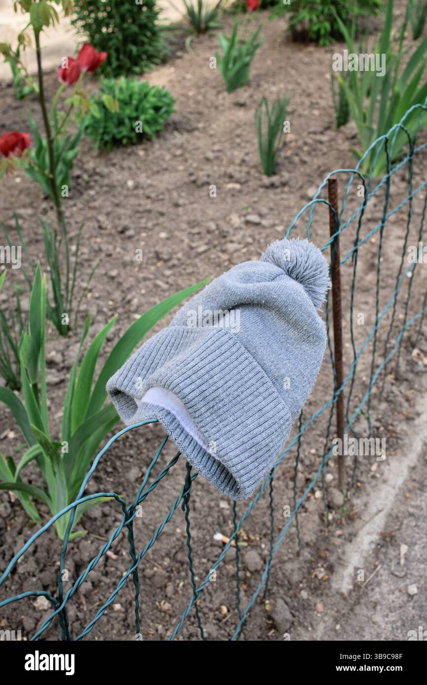Eine urbane Szene, in der ein verlorener grauer Kinderhut am Zaun eines Vorgartens hängt, damit der Besitzer ihn finden kann. Stockfoto Eine urbane Szene, in der ein verlorener grauer Kinderhut am Zaun eines Vorgartens hängt, damit der Besitzer ihn finden kann. Stockfoto