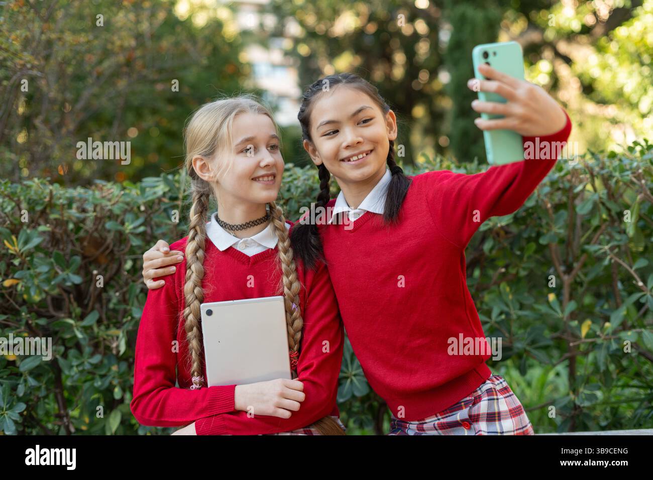 Zwei lächelnde Schüler machen draußen ein Selfie mit Smartphone Stockfoto