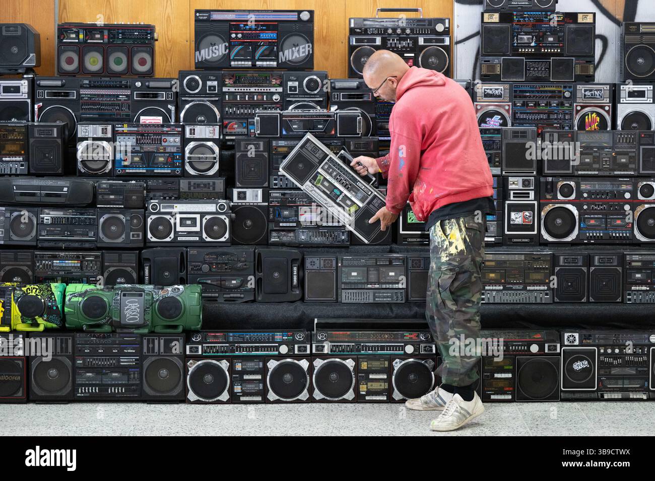 Dresden, Deutschland. Mai 2025. Sebastian Girbig durchsucht seine Sammlung von rund 60 tragbaren Musiksystemen, umgangssprachlich auch Boomboxen genannt, in der ehemaligen Robotron-Kantine. Die Sammlung ist Teil des erstmals stattfindenden Hip-Hop-Festivals ALL4/1, das bis zum 11. Mai 2025 die facettenreiche Hip-Hop-Kultur in Dresden präsentieren soll. Quelle: Sebastian Kahnert/dpa/Alamy Live News Stockfoto