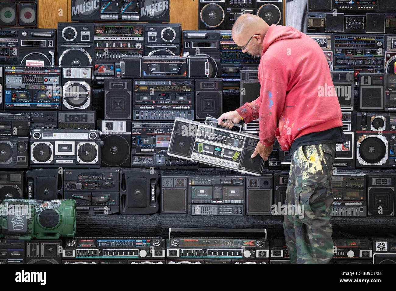 Dresden, Deutschland. Mai 2025. Sebastian Girbig durchsucht seine Sammlung von rund 60 tragbaren Musiksystemen, umgangssprachlich auch Boomboxen genannt, in der ehemaligen Robotron-Kantine. Die Sammlung ist Teil des erstmals stattfindenden Hip-Hop-Festivals ALL4/1, das bis zum 11. Mai 2025 die facettenreiche Hip-Hop-Kultur in Dresden präsentieren soll. Quelle: Sebastian Kahnert/dpa/Alamy Live News Stockfoto
