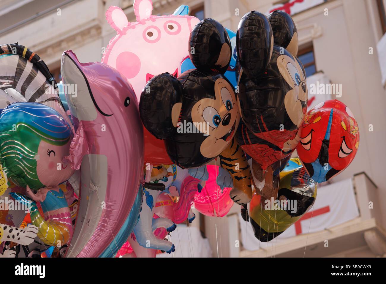Alcoy, Spanien, 05.03.2025: Straßenhändler verkaufen Heliumballons mit Kinderfiguren in Alcoy während des Moors and Christians Festivals Stockfoto